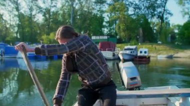 Eski beyaz kayıktaki adam gün doğumunda kürek çekiyor.