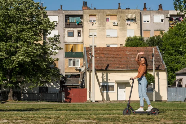 Молода Красива Дівчина Їде Електричному Скутері Через Міське Поселення Махаючи — стокове фото