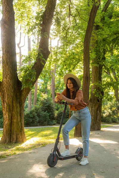 Egy Fiatal Gyönyörű Lány Kalapban Elektromos Robogója Mellett Miközben Gépel — Stock Fotó