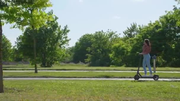 Mulher Bonita Nova Monta Uma Scooter Elétrica Através Parque Ambiente — Vídeo de Stock