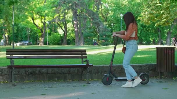 Uma Jovem Que Chega Parque Scooter Elétrico Push Senta Banco — Vídeo de Stock