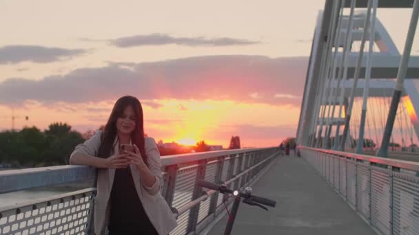Молодая Улыбающаяся Женщина Опирается Забор Моста Печатает Телефоне Рядом Ней — стоковое видео