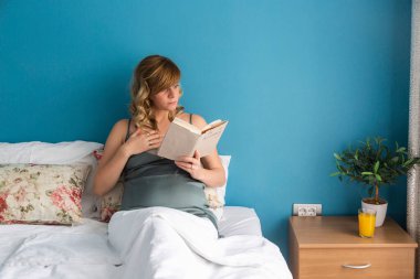 Hamile bir kadın, bir kitapta bir şeyler okurken yarı-oturma pozisyonunda oturan bir kadını hayrete düşürdü. Okuduğu bir şey onu heyecanlandırmış gibi..