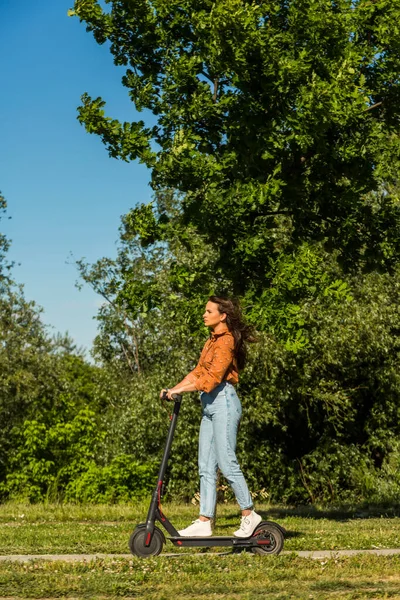 아름다운 여성이 스쿠터를 공원과 환경을 지나는데 장면에서 그녀의 머리카락에 바람이 — 스톡 사진