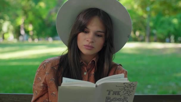 Şapkalı Genç Güzel Bir Kadın Bir Bankta Oturmuş Kitap Okuyor — Stok video