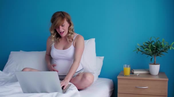 Dizüstü Bilgisayarı Üzerinde Çalışırken Yatağında Oturan Gülümseyen Mutlu Hamile Beyaz — Stok video