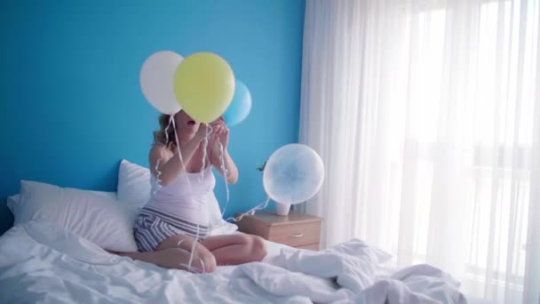 一个快乐的孕妇躺在床上 手里拿着几只气球 上面写着 是个男孩 — 图库视频影像
