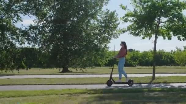 Młoda Piękna Kobieta Jeździ Skuterze Elektrycznym Przez Miejską Osadę Zielonym — Wideo stockowe