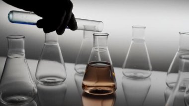Erlenmeyer şişesine mavi renkli damlalar dökülüyor.