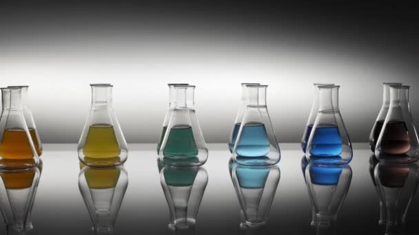空的和混合颜色的液体填充的Erlenmeyer瓶 反映在桌子上 — 图库视频影像