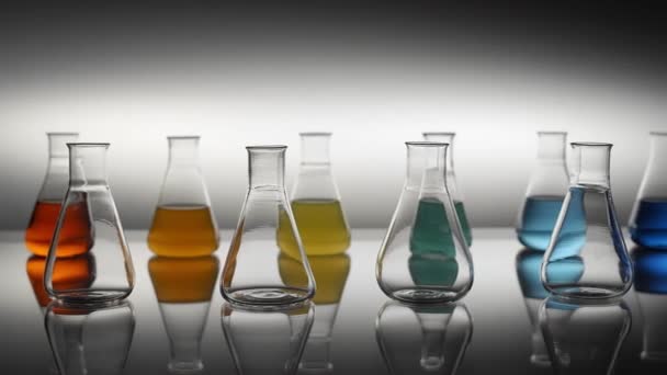 空的和混合颜色的液体填充的Erlenmeyer瓶 反映在桌子上 — 图库视频影像