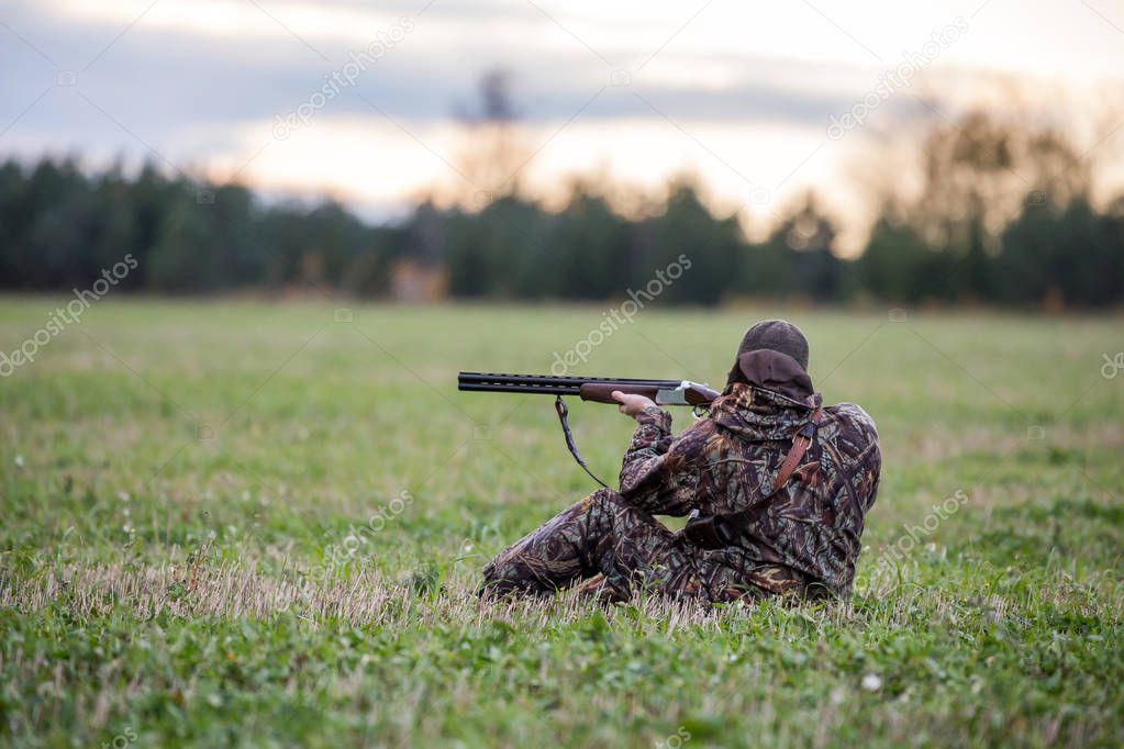 Hunter sitting on the grass and going to shoot