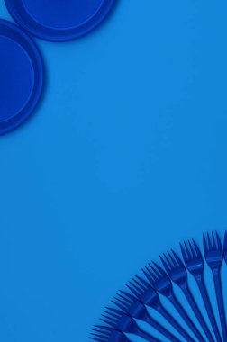 Tek kullanımlık plastik kaplar, mavi zemin üzerinde çatallar, klasik mavi renk, dikey varyasyon, kopyalama alanı