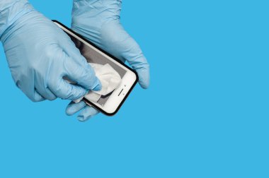 Cep telefonunu sterilize eden bir kadın, virüsün yayılmasını önlemek için bir musluğa alkol bazlı antiseptik sprey sıkar.