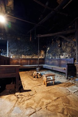 300 yıldan fazladır eski bir mutfak. Tenceresi ahşap bir kemer ve zincirlerle sarkıyor. Etrafında bir tabure ve dikey bir fotoğrafla ateş yakıyor..