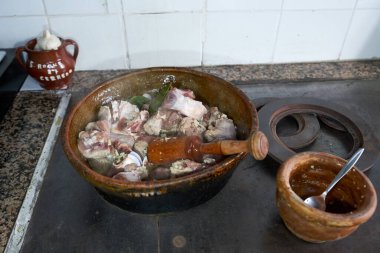 Tipik bir kuzu güveç tarifi sarımsak ve defne yaprağı yanında da bir kil kase dolusu sarımsak ve mutfakta pişirilen kaşıkla ahşap bir havan topu.