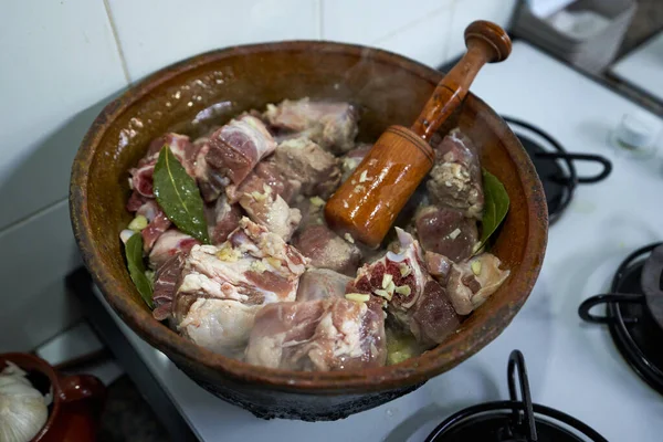 Kuzu etli antika güveç, sarımsak ve sobada pişirilirken ahşap havan.