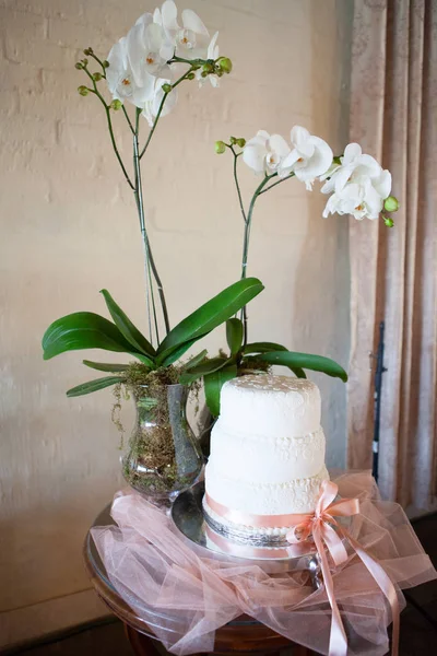 Bruidstaart en bloemen op tafel in de receptiezaal Rechtenvrije Stockafbeeldingen