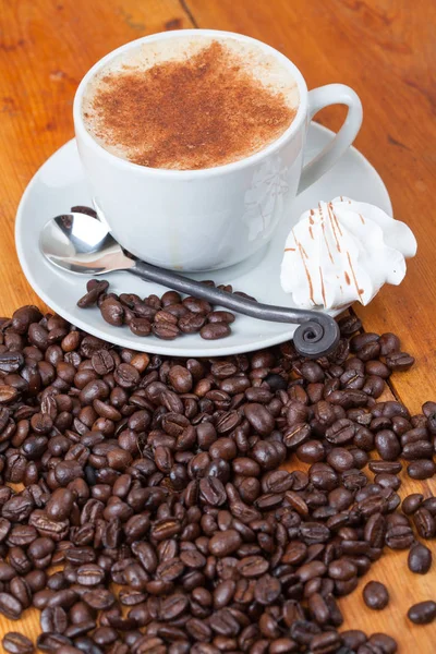 Cappuccino fraîchement brassé entouré de grains de café Photos De Stock Libres De Droits