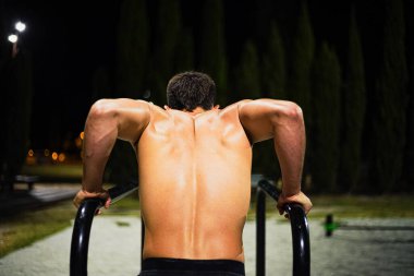 Gece antrenmanında üstsüz, kaslı genç adam eğitimi. Halka açık bir bar parkında. Daldırıyorum. Görüntü Yönetmeni:.