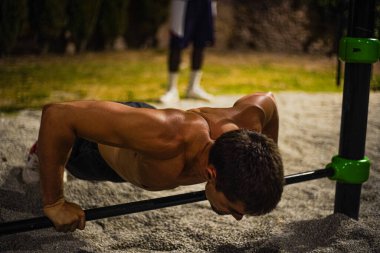Gece antrenmanında üstsüz, kaslı genç adam eğitimi. Halka açık bir bar parkında. Şınav çekiyorum. Görüntü Yönetmeni:.