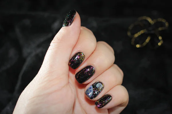 Black manicure with flames in the form of space, on the thumb there is a drawing of the planet  and stars. Very effective design, background in tone to manicure - the Milky Way.
