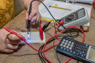 Electrical engineer works at his workplace with a voltage tester - close-up clipart