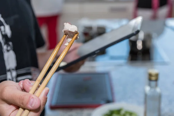 デジタル料理書による調理指導 肉とタブレットで箸の閉鎖 — ストック写真
