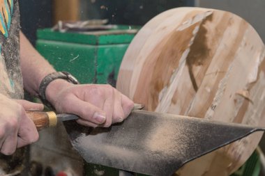 Carpenter turns wooden disk - close-up clipart
