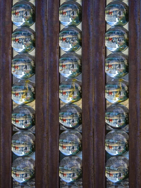 Rows of glass balls in which the environment is reflected, iron bars between them - stylized image, oil painting
