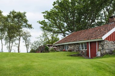 Kırmızı kapılı ve Norveç'te çatı ile eski küçük taş ev