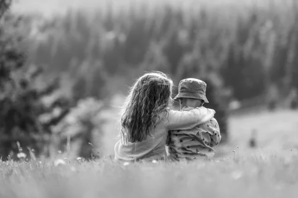 少年少女屋外 フィールド草原で兄と妹の一緒に座って抱いてと黒と白 — ストック写真