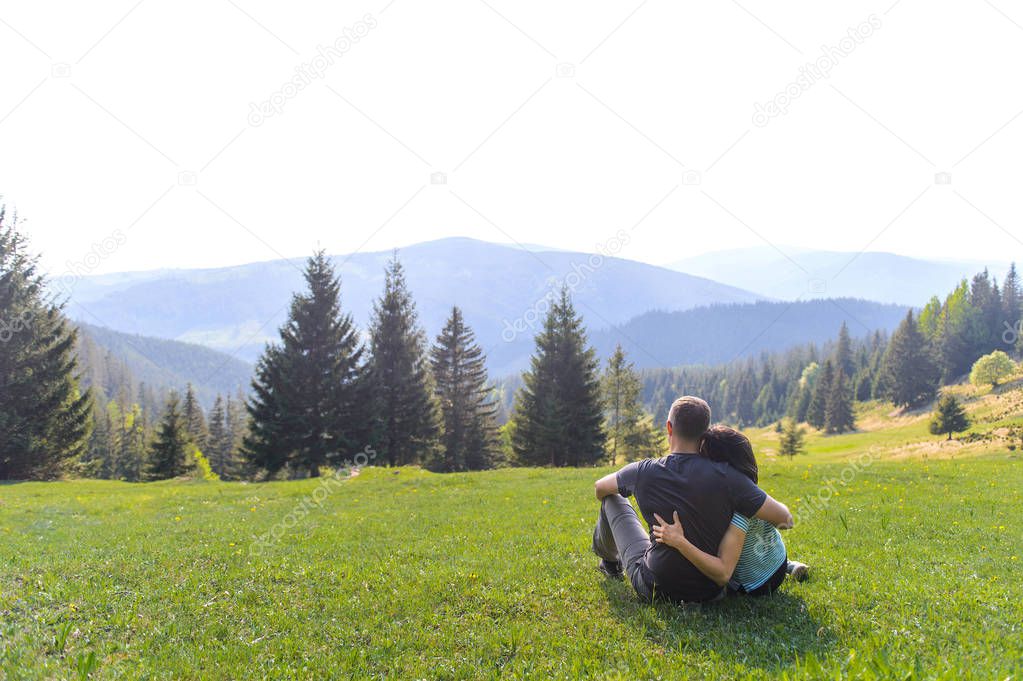 man and woman hugging and enjoying view on mountains and pine forest