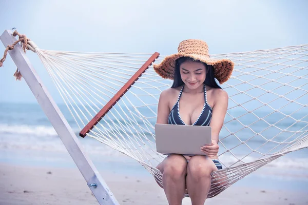 sexy bikini asian woman use laptop on tropical beach, travel the