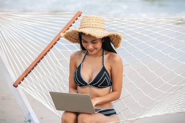 sexy bikini asian woman use laptop on tropical beach, travel the