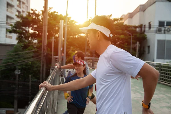 Group runner stretching arms before running