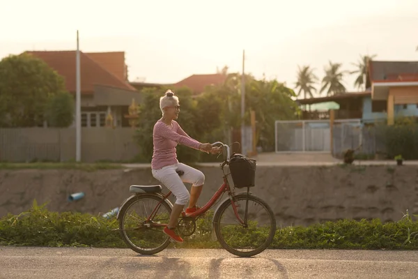 Senior woman with bicycles outside in sunset