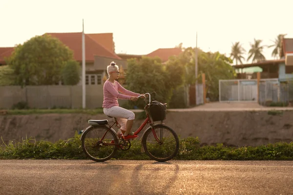 Senior woman with bicycles outside in sunset