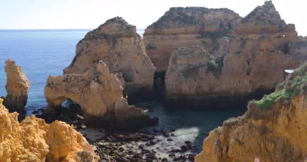 ポンタ ピエダデ 南ポルトガル ラゴス 岩だらけの海岸で有名な場所 大西洋 シャープの波岩 紺碧の水 黄色花 アーチ — ストック動画