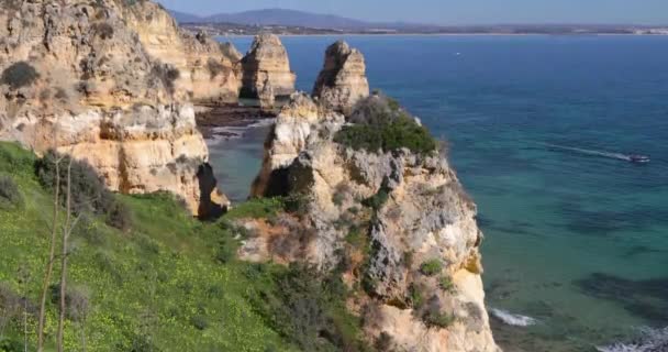 ポンタ ピエダデ 南ポルトガル ラゴス 岩だらけの海岸で有名な場所 大西洋 シャープの波岩 紺碧の水 黄色花 アーチ — ストック動画