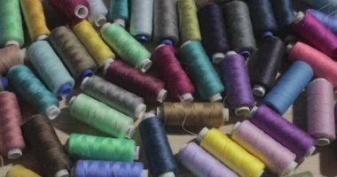 Farklı renkte dizgilerin yavaş çekim videosu bir masanın üzerinde yatar, birisi masanın üzerine iplik rulosu atar.