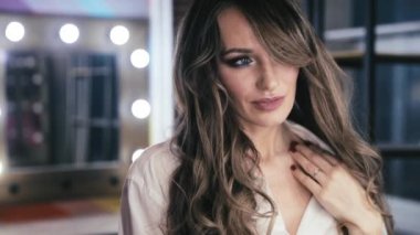 uzun kıvırcık saç flaunts ile güzel genç kız ve bir ayna önünde kapalı gösterir, flört, flört, gülümsüyor, boğucu bakmak, mutlu, kendini memnun, güzel makyaj, seksi dudaklar