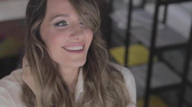 uzun kıvırcık saç flaunts ile güzel genç kız ve bir ayna önünde kapalı gösterir, flört, flört, gülümsüyor, boğucu bakmak, mutlu, kendini memnun, güzel makyaj, seksi dudaklar