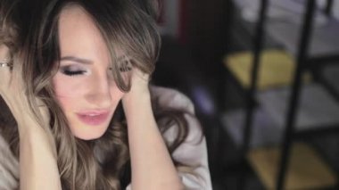 uzun kıvırcık saç flaunts ile güzel genç kız ve bir ayna önünde kapalı gösterir, flört, flört, gülümsüyor, boğucu bakmak, mutlu, kendini memnun, güzel makyaj, seksi dudaklar