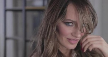 uzun kıvırcık saç flaunts ile güzel genç kız ve bir ayna önünde kapalı gösterir, flört, flört, gülümsüyor, boğucu bakmak, mutlu, kendini memnun, güzel makyaj, seksi dudaklar