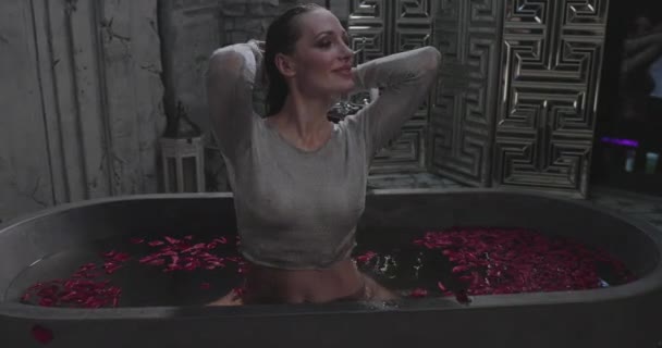 这个年轻貌美的姑娘坐在盛满玫瑰的高水浴中 在浴室里炫耀炫耀 自鸣得意 性感的嘴唇 湿透的头发 — 图库视频影像