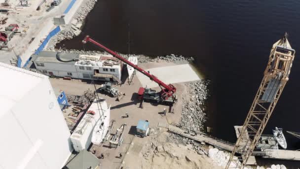 Russland, St.Petersburg, 26. Mai 2020: Der große Industriekran hebt das Segelboot und treibt es an, Beginn einer Segelsaison, Drohnen-Aussichtspunkt, Hafen Hercules — Stockvideo