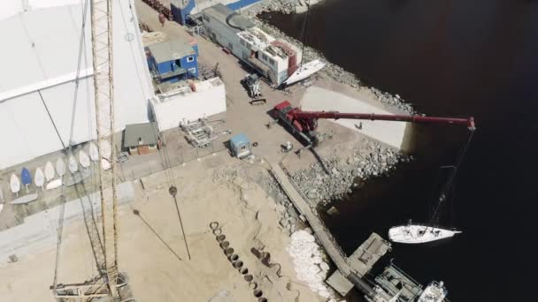 La grande gru industriale solleva la barca a vela e la galleggia, l'inizio di una stagione di vela, punto di vista drone, porto Hercules — Video Stock