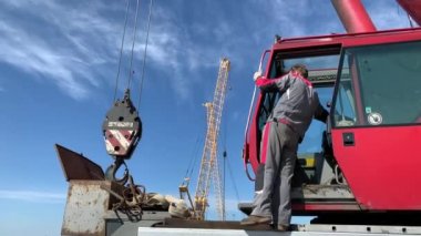 Rusya, St.Petersburg, 26 Mayıs 2020: Küçük yelkenli teknelerin kaldırılması ve suya inişleri için büyük bir endüstriyel vinç hazırlıyor, vinç yöneticisi vinci çalışmaya hazırlıyor