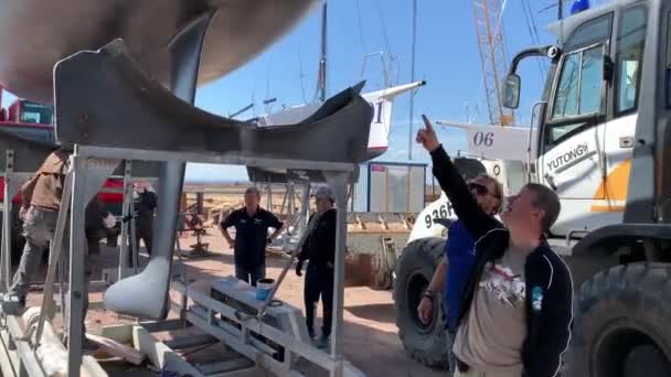 Russia, St.Petersburg, 26 May 2020: The team discusses the plan of work standing under the lifted sailboat — Stock Video